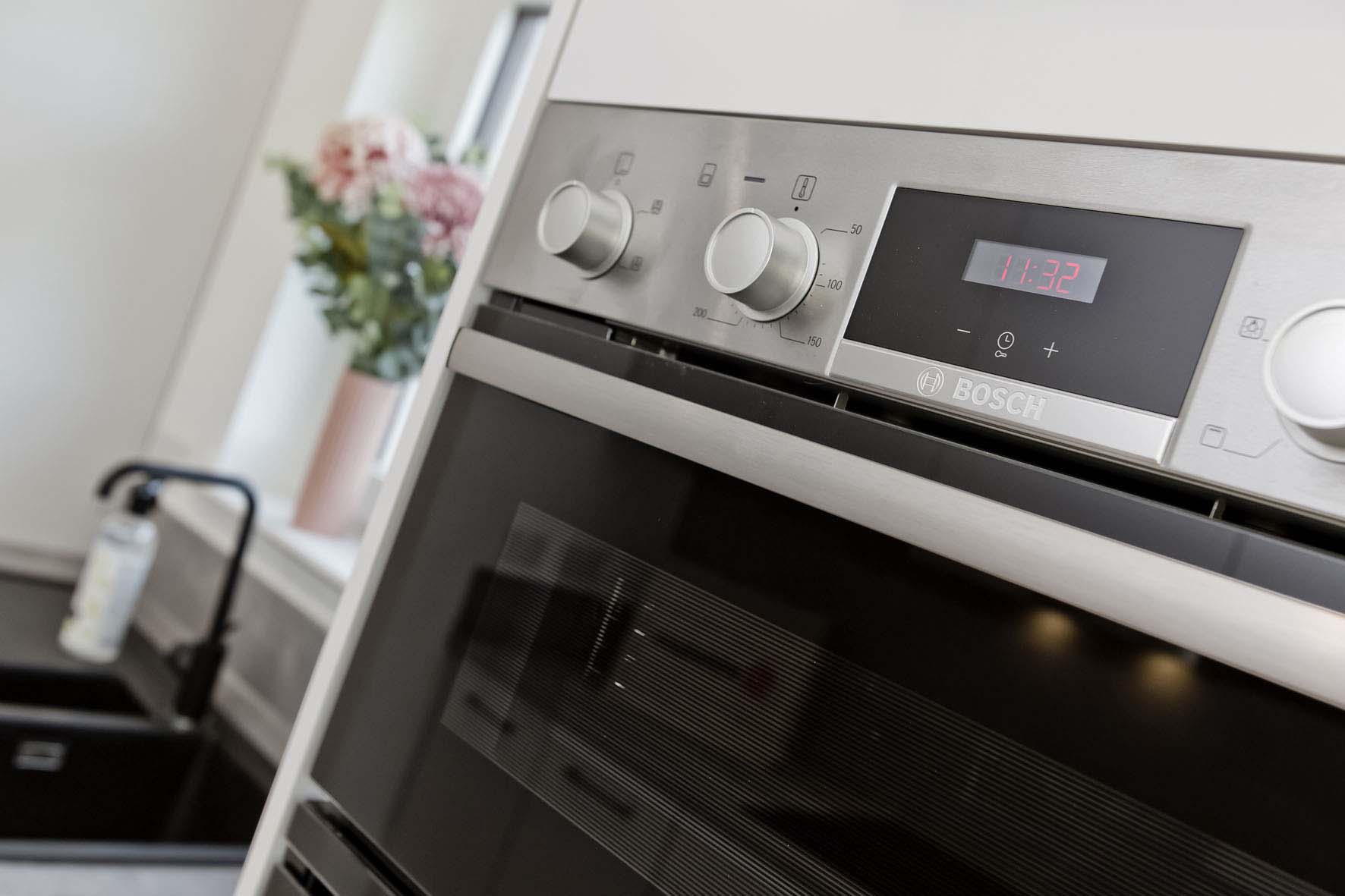 Bosch integrated oven with black sink and tap in background with flowers on the window cill in a new home, Scottish Borders
