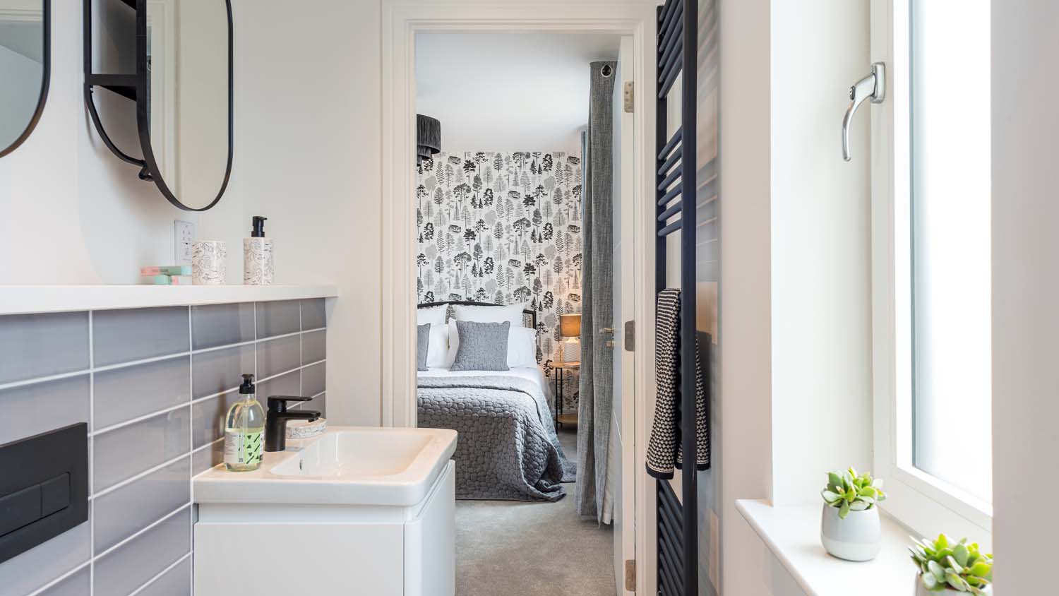 View from en-suite to master bedroom of a new home in the Scottish Borders. The bathroom and bedroom have grey and white styling
