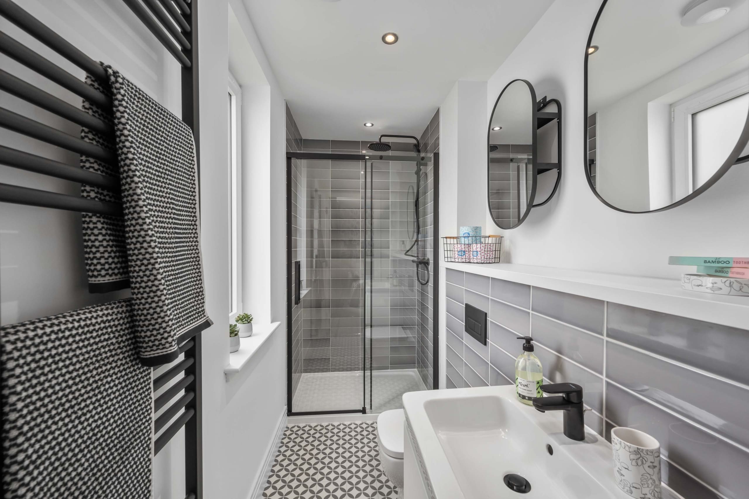 Modern stylish en-suite shower room with grey tiles, white sanitary ware and black fittings in a new home in the Borders