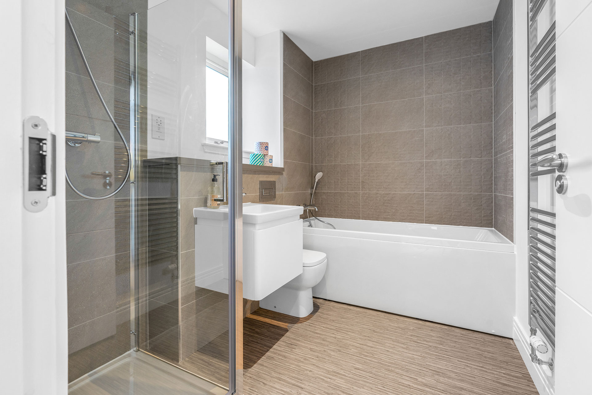 Family bathroom in a 4 bedroom new build home in Kirkcaldy. White bath to rear and sink, toilet and shower to left wall and chrome radiator to the right wall