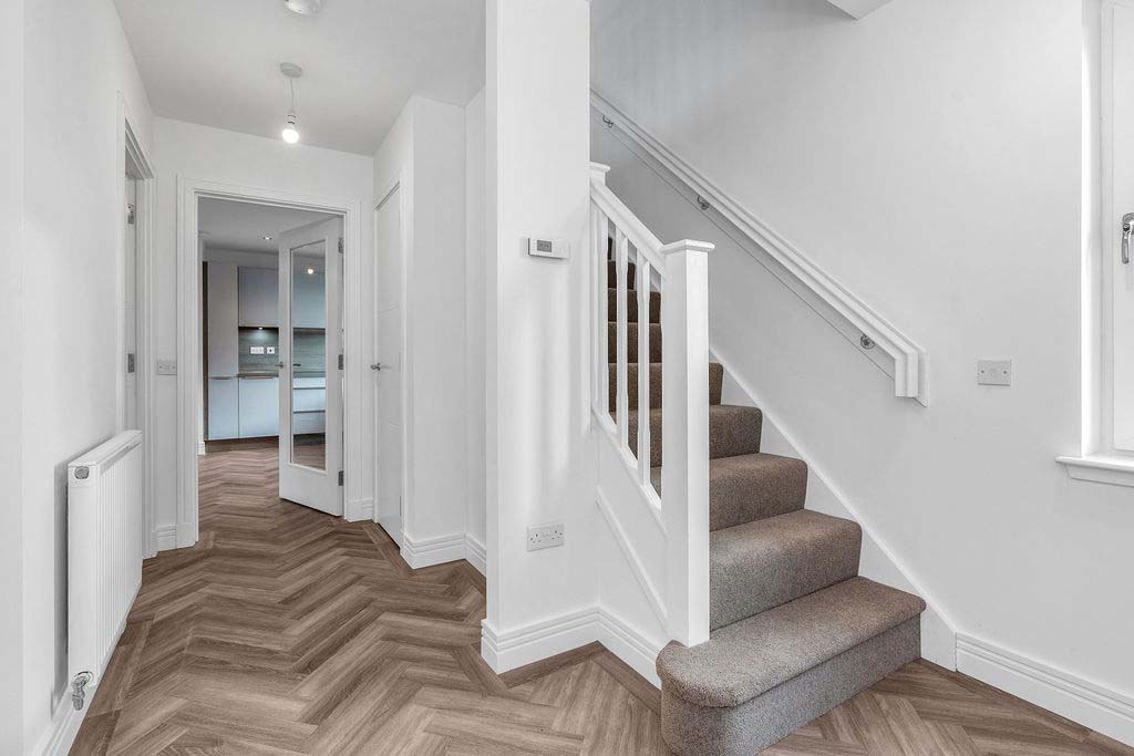 Entrance hallway with stairs to first floor and door into the open-plan kitchen/dining/living area in new home for sale Borders