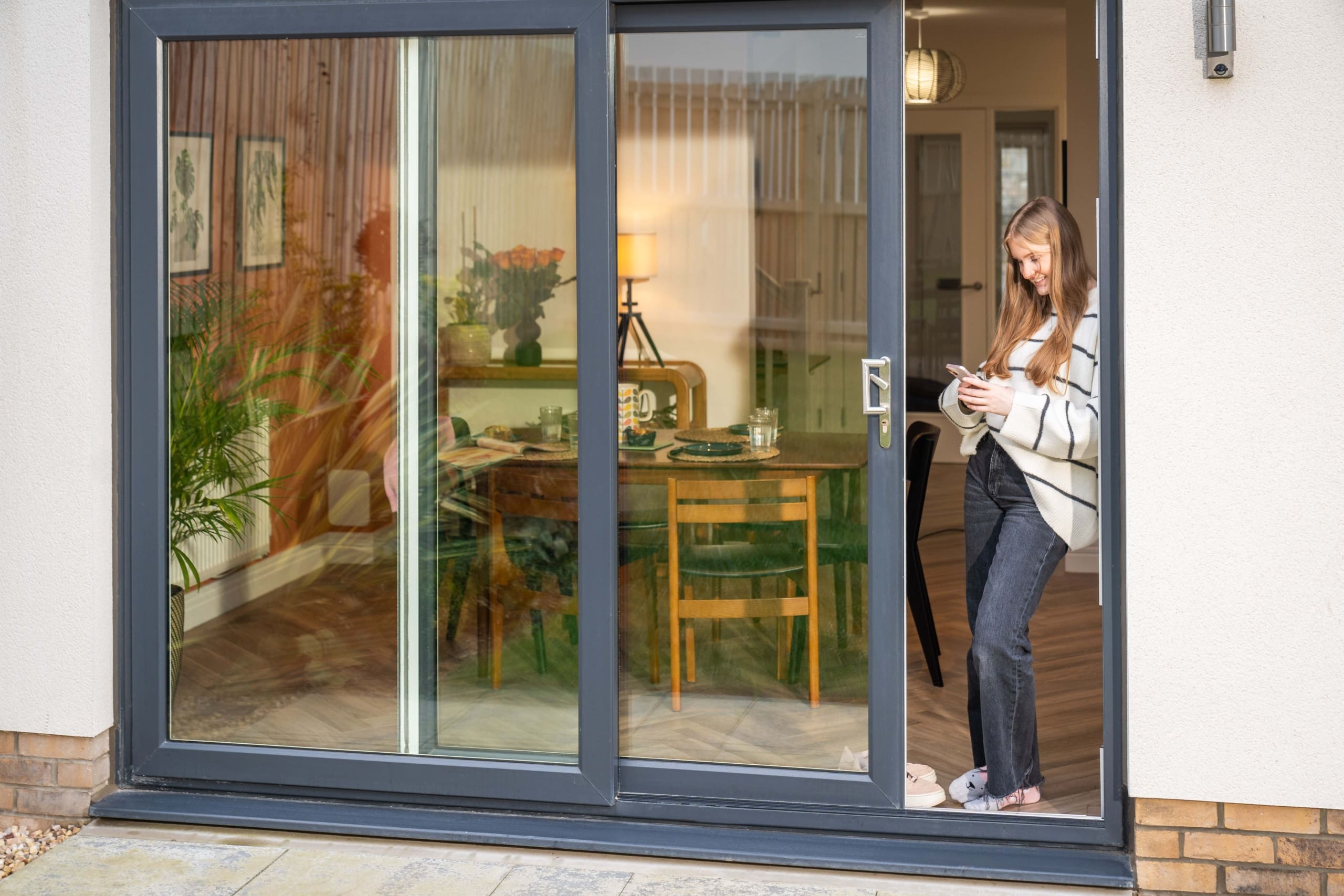 Girl stood in doorway of double patio doors, leading into dining room of a new build home in the Borders