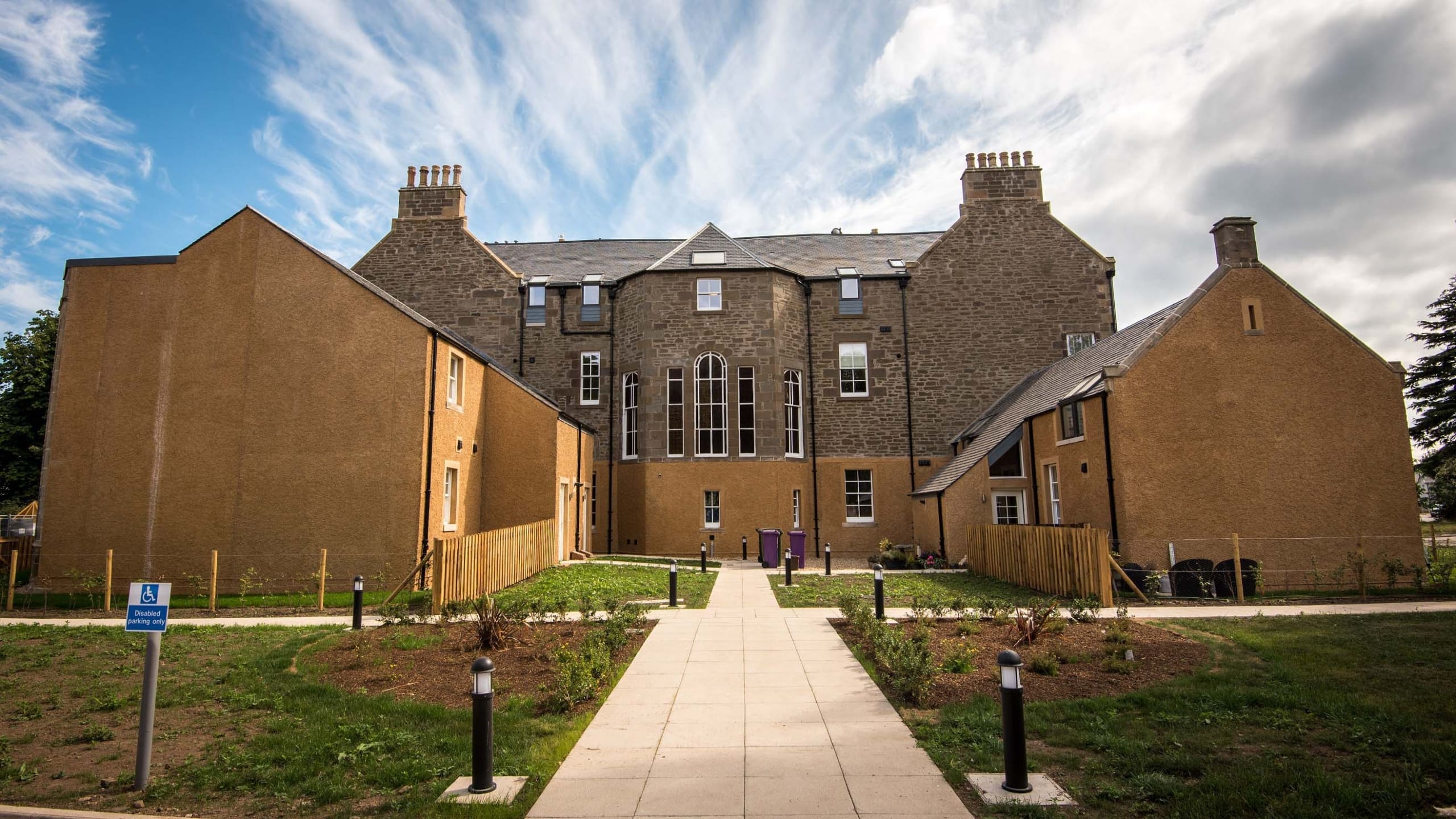 Rear view of renovated building with extensions to left and right with pathway in centre of the image. Converted to new homes near Dundee