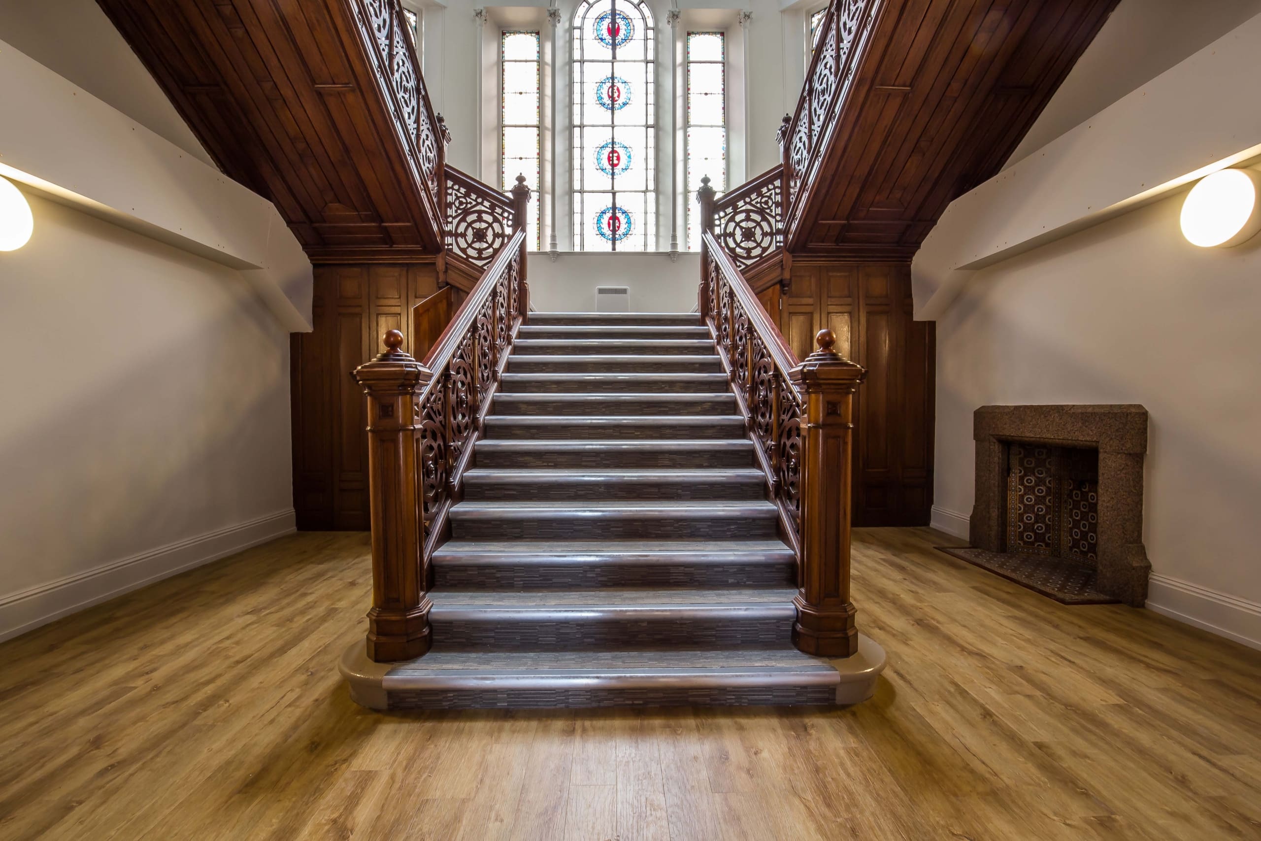 Dark wooden staircase to landing which had large stained glass windows in renovated building for new homes near Dundee