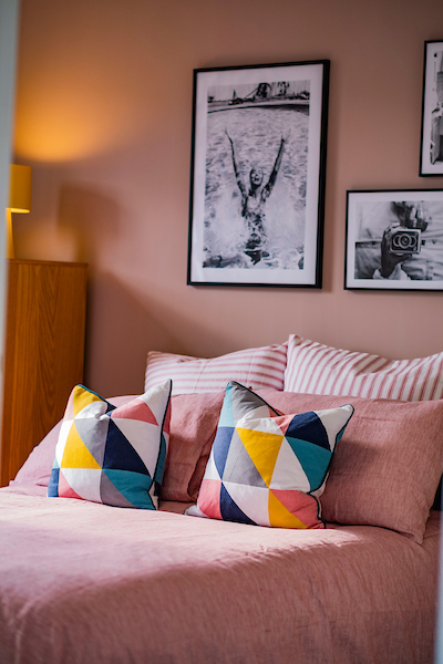 Bedroom with pink bedding and colourful cushions