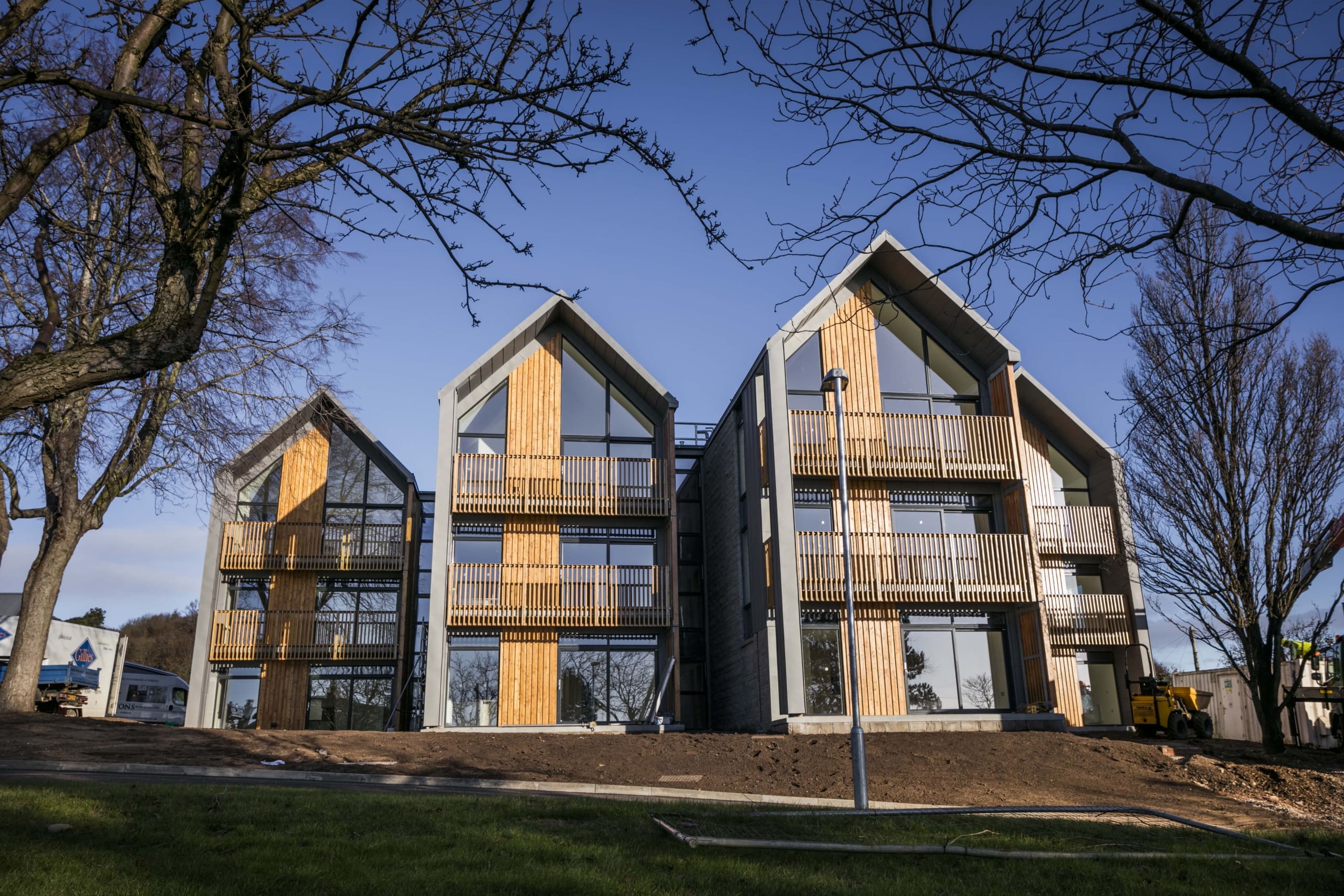 New build houses in three storey buildings. Blue skies and trees to foreground in new build development in Dundee