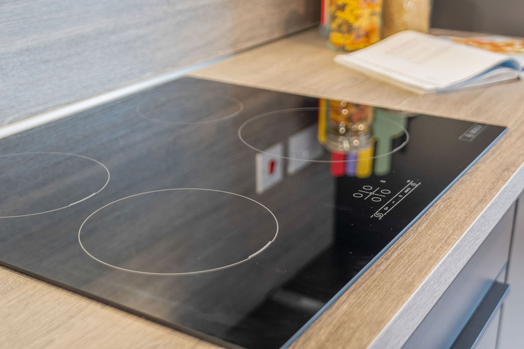 Kitchen worktop in a wood effect with a integrated bosch hope with cookery book and jars of food to the background