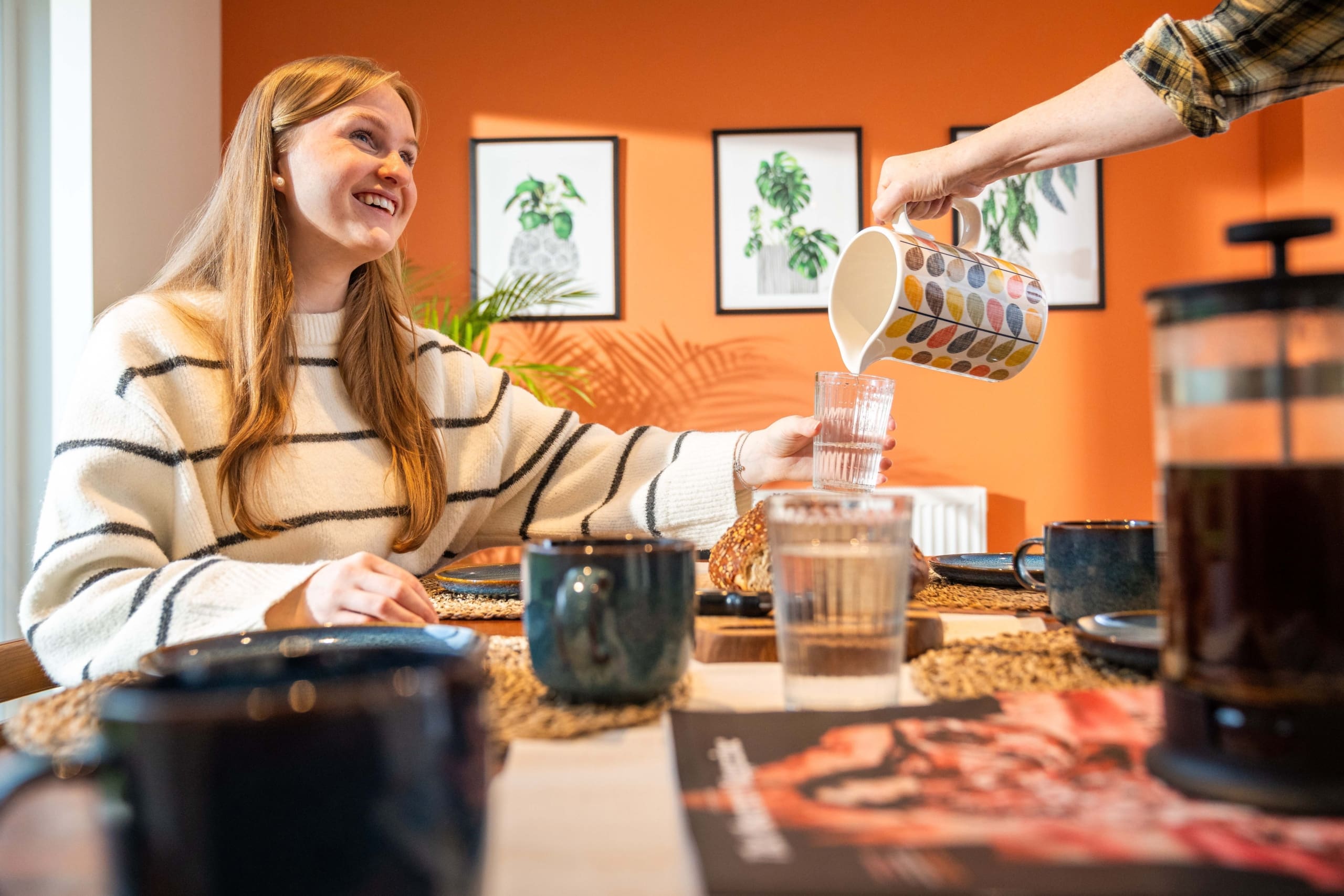 Girl at dining table being poured a drink in brightly coloured room in a new home for sale in the Borders