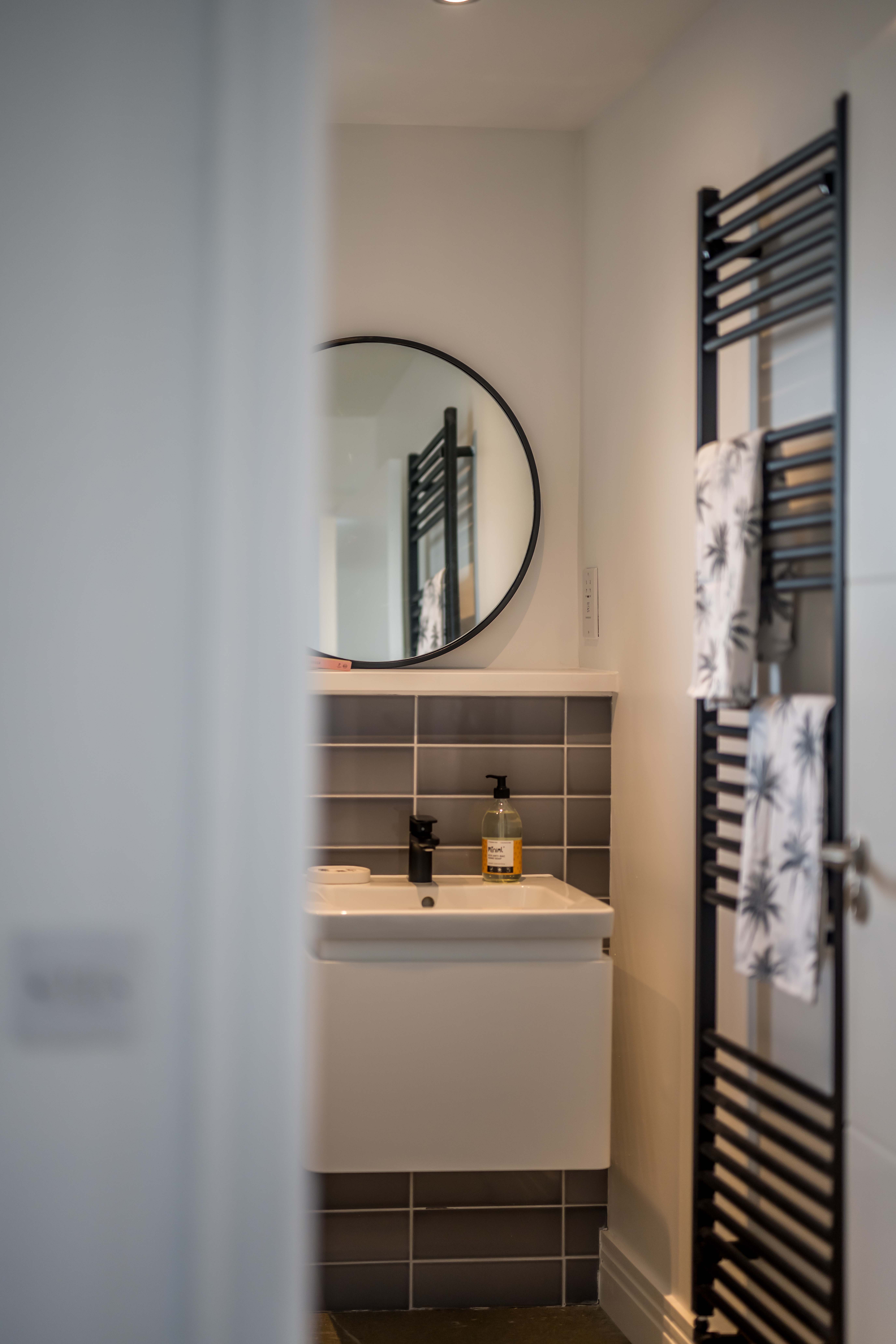 Grey tiled wall in bathroom of new home with white sink and chrome taps
