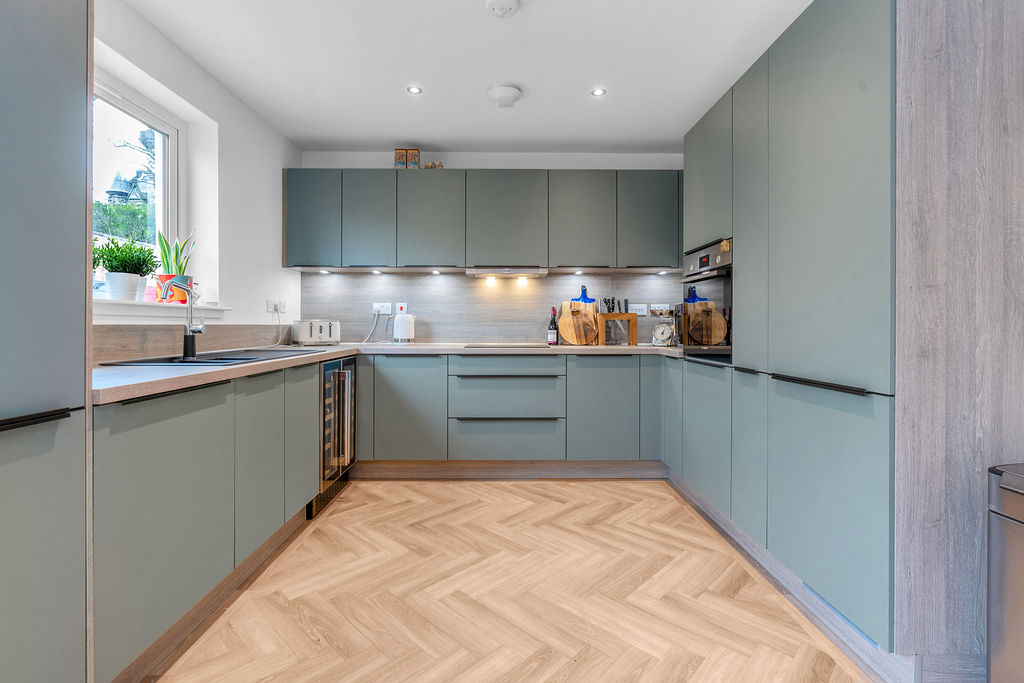 Kitchen in modern new build home in Kirkcaldy. Green cabinets and wooden floor